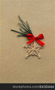 Creative christmas concept photo of a snowflake made of qulling paper on brown background.