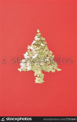 Creative Christmas decoration Tree from small shiny spruces on a red background with copy space. Greeting holiday card.. New Year Tree handmade from small sparkly fir.