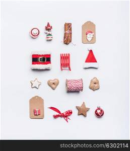 Creative Christmas layout made of craft paper tags, cookies, red Christmas winter decoration: Santa hat, sleigh, cinnamon sticks on white desk background, top view, flat lay. Holiday pattern