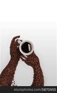 Creative coffee bean art; human hands made of roasted coffee beans, holding a coffee cup on grey background.