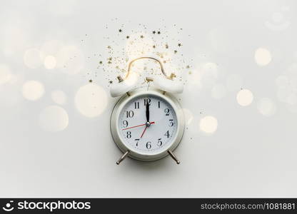 Creative composition with alarm clock and golden stars confetti on white background. New Year Christmas Top view flat lay