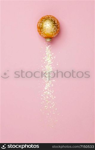 Creative composition with Christmas ball and golden stars confetti on pink background. New Year Christmas Top view flat lay