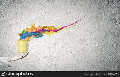 Creative concept. Close up of businesswoman holding bucket with paint splashes
