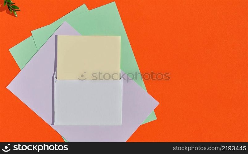 Creative concept for congratulatory letter, greeting card template. Horizontal layout with copy space. Postcard mockup with white envelope and multi-colored writing paper on an orange burnt background
