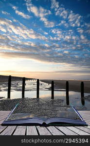 Creative concept pages of book Beautiful sunrise reflected in low tide water pools on beach landscape