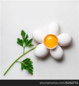 Creative concept photo of a flower made of eggs and parsley on white background.