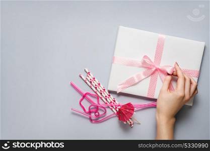 Creative concept photo of a present box with bow and cocktail straws on grey background.