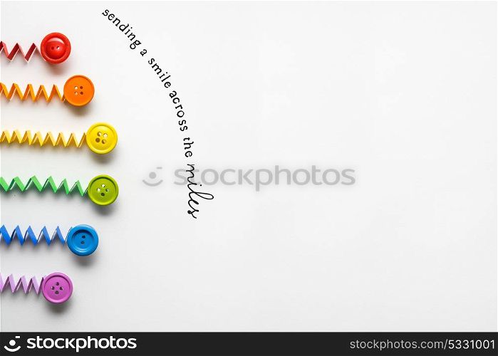 Creative concept photo of a rainbow made of paper and buttons on grey background.