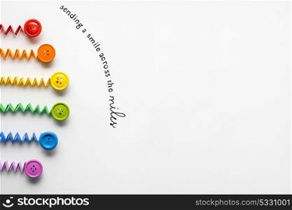 Creative concept photo of a rainbow made of paper and buttons on grey background.