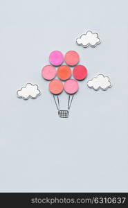 Creative concept photo of aerostat made of cosmetics on grey background.