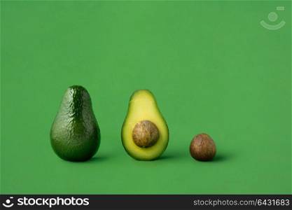 Creative concept photo of avocados on green background.