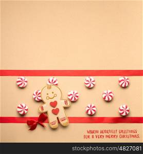 Creative concept photo of christmas candy and gingerbread man on brown background.