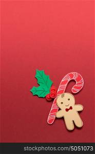 Creative concept photo of christmas candy and gingerbread man on red background.
