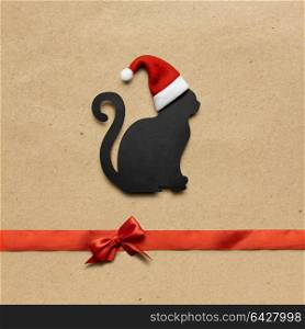 Creative concept photo of christmas cat in the hat with sign on brown background.