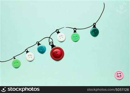 Creative concept photo of christmas lights made of buttons on green background.