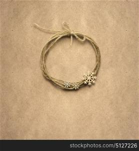 Creative concept photo of christmas wreath made of rope with snowflakes on brown background.