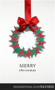 Creative concept photo of christmas wreath with bow made of paper on white background.