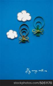 Creative concept photo of clouds and aerostats made of paper on blue background.
