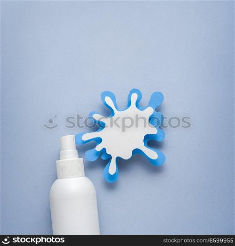 Creative concept photo of cosmetic bottle with splashing liquids made of paper on blue background.