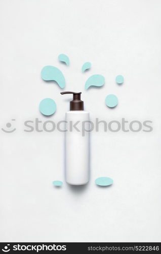 Creative concept photo of cosmetic bottle with splashing liquids made of paper on white background.