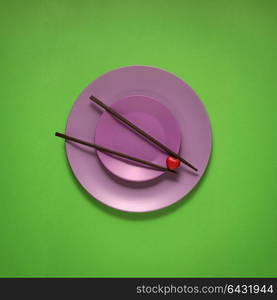 Creative concept photo of kitchenware, painted plate with food on it on green background.