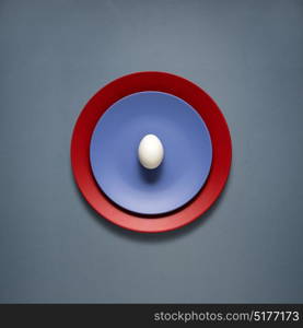 Creative concept photo of kitchenware, painted plate with food on it on grey background.