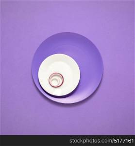 Creative concept photo of kitchenware, painted plate with food on it on purple background.