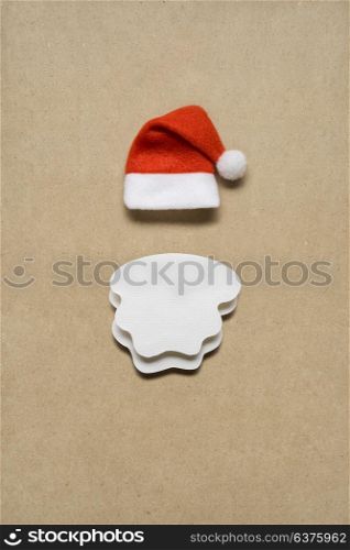 Creative concept photo of santas hat and beard on brown background.