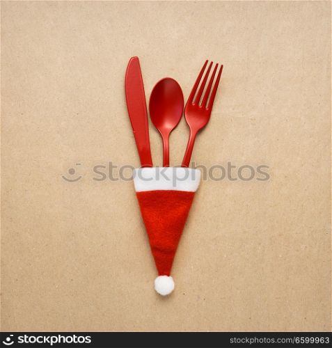 Creative concept photo of tableware christmas hat in on brown background.