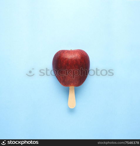 Creative concept still life food diet health photo of apple fruit on stick in shape of ice cream popsicle on blue background.