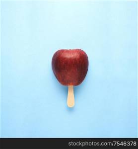 Creative concept still life food diet health photo of apple fruit on stick in shape of ice cream popsicle on blue background.