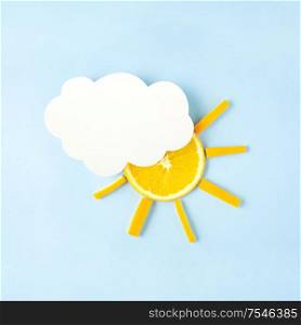 Creative concept still life food diet health photo of orange raw slice in shape of the sun with cloud made of paper on blue background.