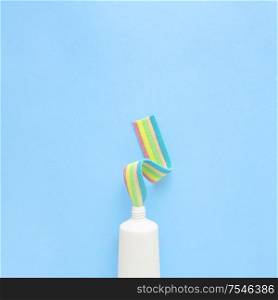 Creative concept still life food health photo of toothpaste tube with jelly marmalade candy marshmallow on blue background.