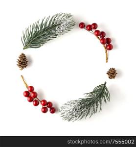 Creative concept still life holiday Christmas photo of pine tree branches and berries in the shape of wreath on white background.