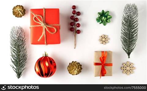 Creative concept still life holiday photo of pine tree branches berries with Christmas toys decorations and present gift boxes on white background.