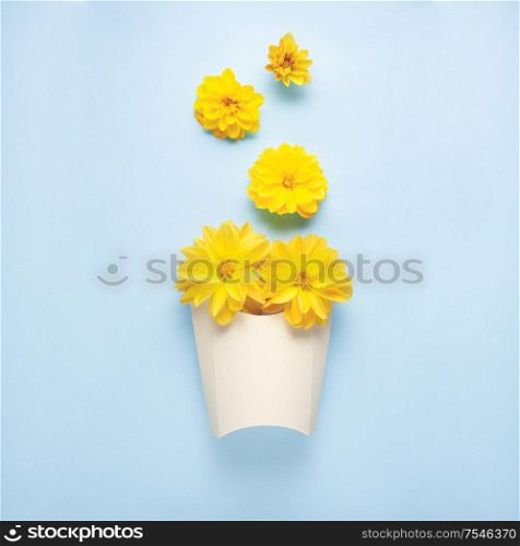 Creative concept still life nature green photo of flowers in bloom with paper fast food box on blue background.