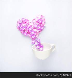 Creative concept still life valentine day photo of flowers in bloom in shape of heart with coffee drink beverage cup mug on grey background.