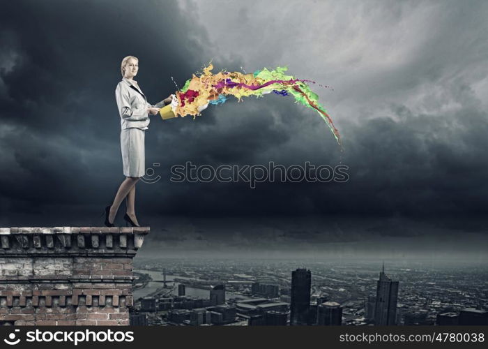 Creative concept. Young businesswoman holding bucket with paint splashes