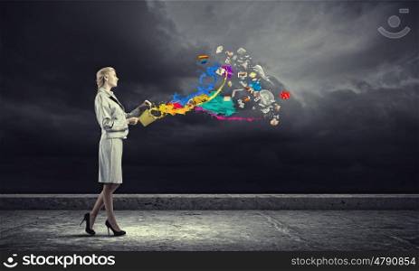 Creative concept. Young businesswoman holding bucket with paint splashes