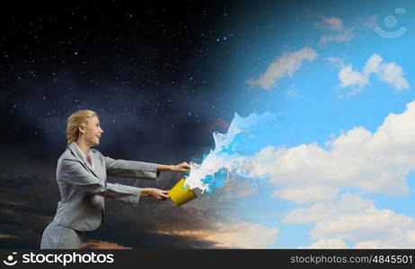 Creative concept. Young businesswoman holding bucket with paint splashes