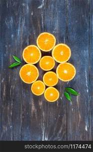 Creative dark style flat lay top view of fresh orange fruit slices on brown wooden table background with copy space. Minimal summer fresh citrus composition for blog or recipe book