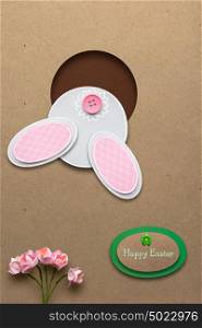 Creative easter concept photo of a rabbit in a hole made of paper on brown background.