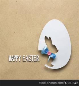 Creative easter concept photo of a rabbit in an egg made of paper on brown background.