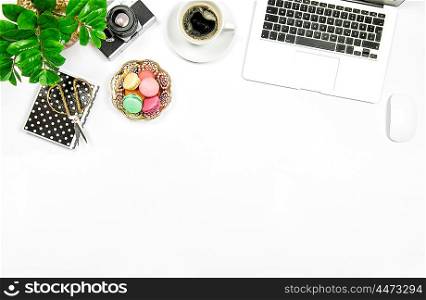 Creative feminine workplace. Coffee, macaroon cookies, laptop computer and green plant on white table background