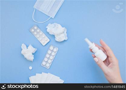 Creative flat lay concept of seasonal spring allergy with napkins, pills, face mask, drops in a bottle and a female hand with copy space background minimal style, template for text