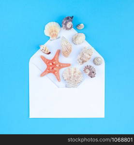 Creative flat lay concept of summer travel vacations. Top view of seashells and starfish on turquoise blue background with postcard mock up and copy space in minimal style, template for text