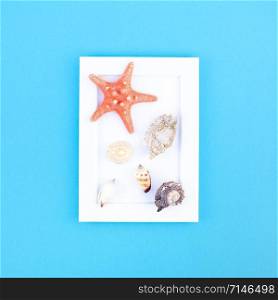 Creative flat lay concept of summer travel vacations. Top view of seashells and starfish on turquoise blue background with white frame mock up and copy space in minimal style, template for text