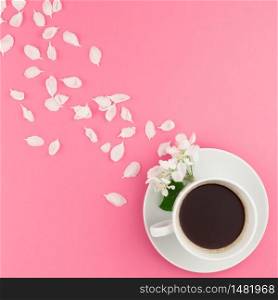 Creative flat lay concept top view of coffee cup and white apple tree flowers petals on pastel pink square background with copy space in minimal style, template for text