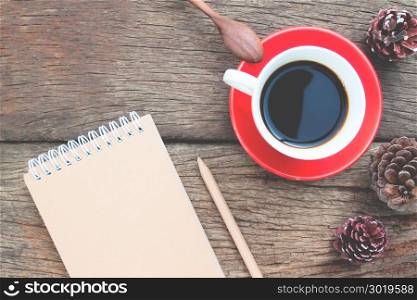 Creative flat lay cup of coffee with craft paper diary on wooden table