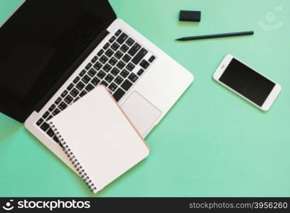 Creative flat lay design of workspace desk with laptop, blank notebook, smartphone and stationery with copy space background